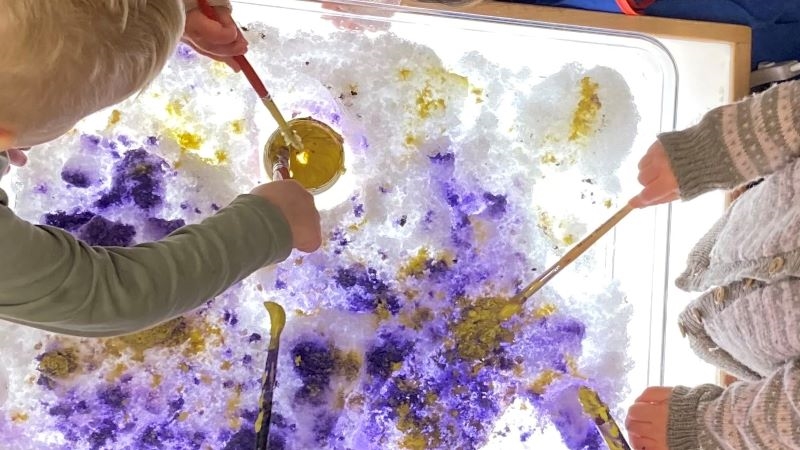 Barn målar med vattenfärg i snö